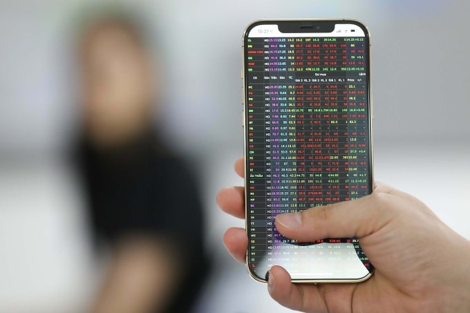 Nhà đầu tư đang theo dõi bảng giá thị trường chứng khoán trên điện thoại. Ảnh: Quỳnh Trần