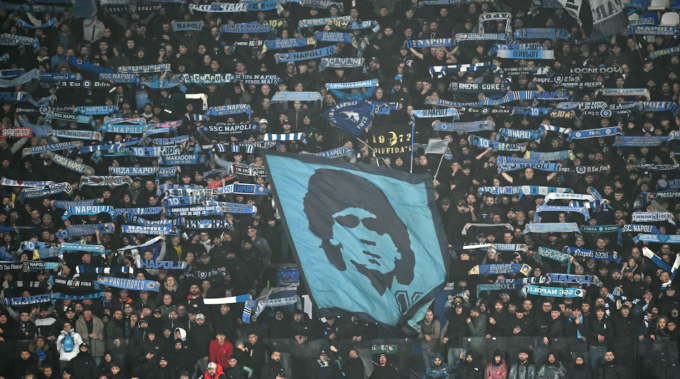 Các CĐV Napoli giơ cao cờ, khăn để tri ân Diego Maradona trong trận thắng Qarabag 2-0 ở lượt năm Champions League trên sân Diego Armando Maradona ngày 25/11/2025. Ảnh: AS