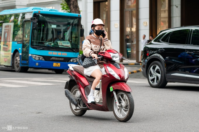 Người đi xe máy dùng điện thoại khi di chuyển tại Hà Nội, tháng 10/2025. Ảnh: Minh Quân