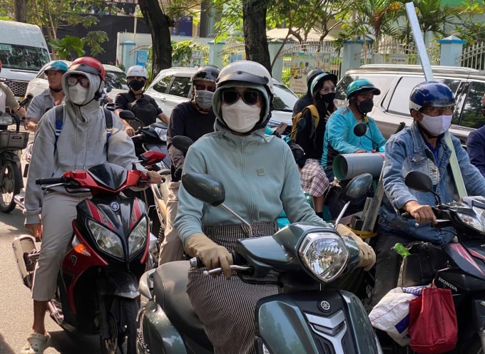 Người đi xe máy mặc thêm áo khoác trên đường Trương Định khi nhiệt độ TP HCM xuống 21 độ C, sáng 27/11.