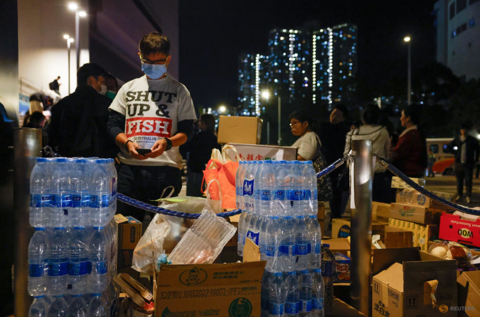 Người dân bên vật dụng cứu trợ cho người sơ tán sau vụ cháy chung cư Wang Fuk Court tại Hồng Kông, ngày 27/11. (Ảnh: Reuters)