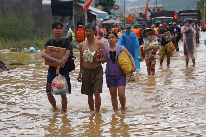 Người dân xã Diên Điền lội nước đi nhận lương thực sau trận lũ. Ảnh: Bùi Toàn