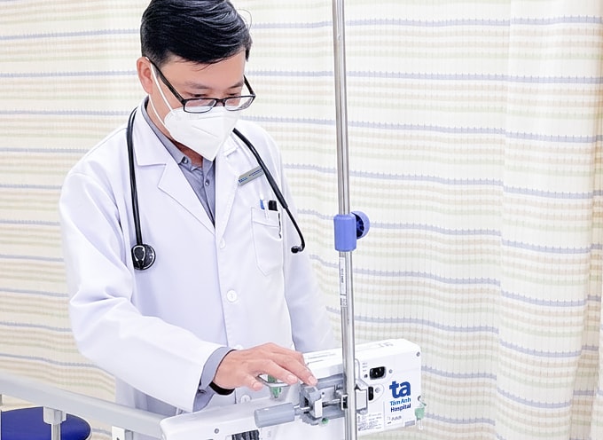 Bác sĩ Thiện điều chỉnh máy truyền thuốc cho người bệnh. Ảnh: Bệnh viện Đa khoa Tâm Anh