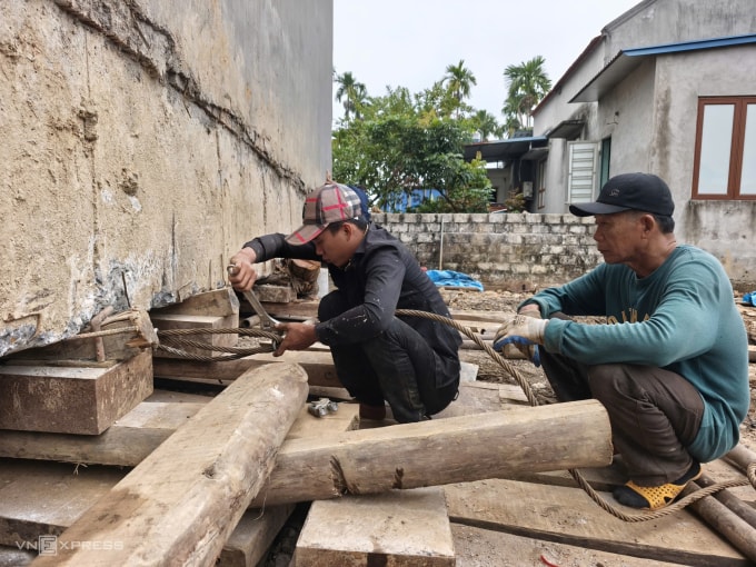 Thợ dùng gỗ, tời kéo, ống sắt để di chuyển ngôi nhà về lô đất của ông Hữu. Ảnh: Lê Tân