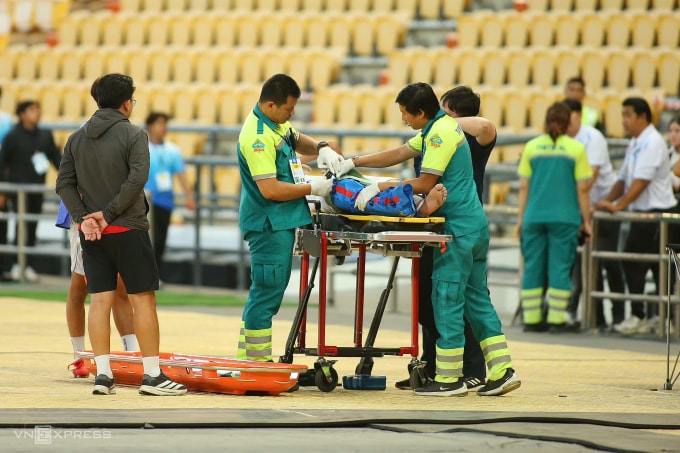 Nhân viên y tế của ban tổ chức SEA Games 33 cố định chân bị gãy cho Phetdavanh Somsanid trước khi đưa lên xe cứu thương chuyển từ sân Rajamangala đến bệnh viện. Ảnh: Đức Đồng
