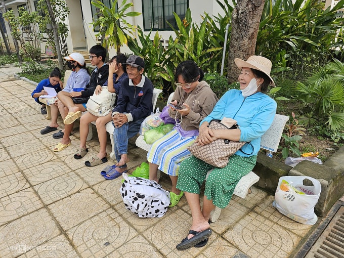 Bà Trần Thị My (áo xanh) cùng gia đình đi tránh lũ tại trường tiểu học Vĩnh Hiệp, phường Tây Nha Trang. Ảnh: Bùi Toàn