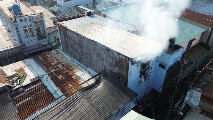 Khói từ đám cháy trong ngôi nhà bốc ra khe tường phía sau. Ảnh: Đình Văn