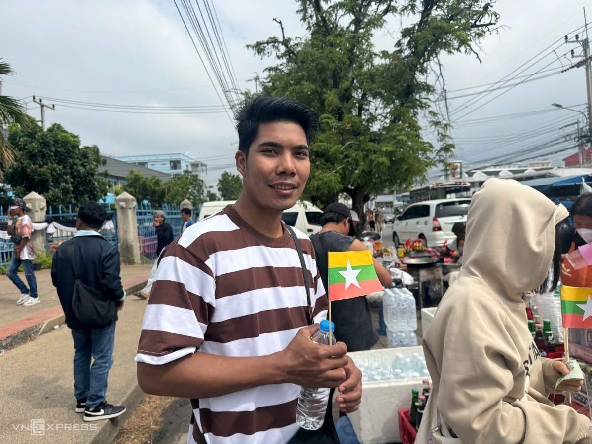 Một CĐV nam Myanmar mua nước và mang theo lá cờ nhỏ chuẩn bị vào sân.