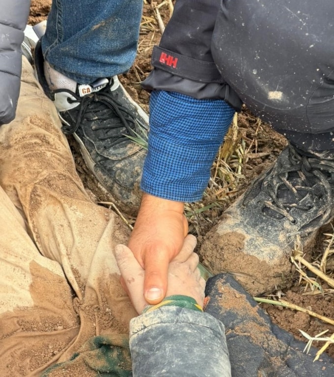 Nhân viên cứu hộ nắm tay cậu bé sau cuộc giải cứu. Ảnh: Onedio