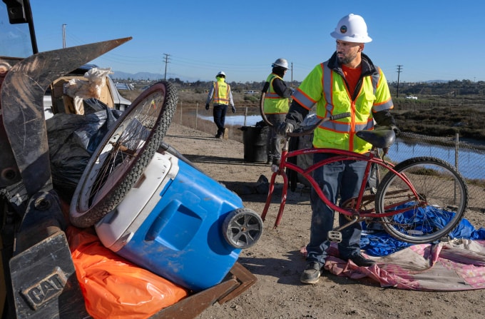 Nhân viên quận Cam dọn dẹp khu lều trại của người vô gia cư dọc đầm lầy sông Santa Ana, ngày 10/12. Ảnh: OC Register