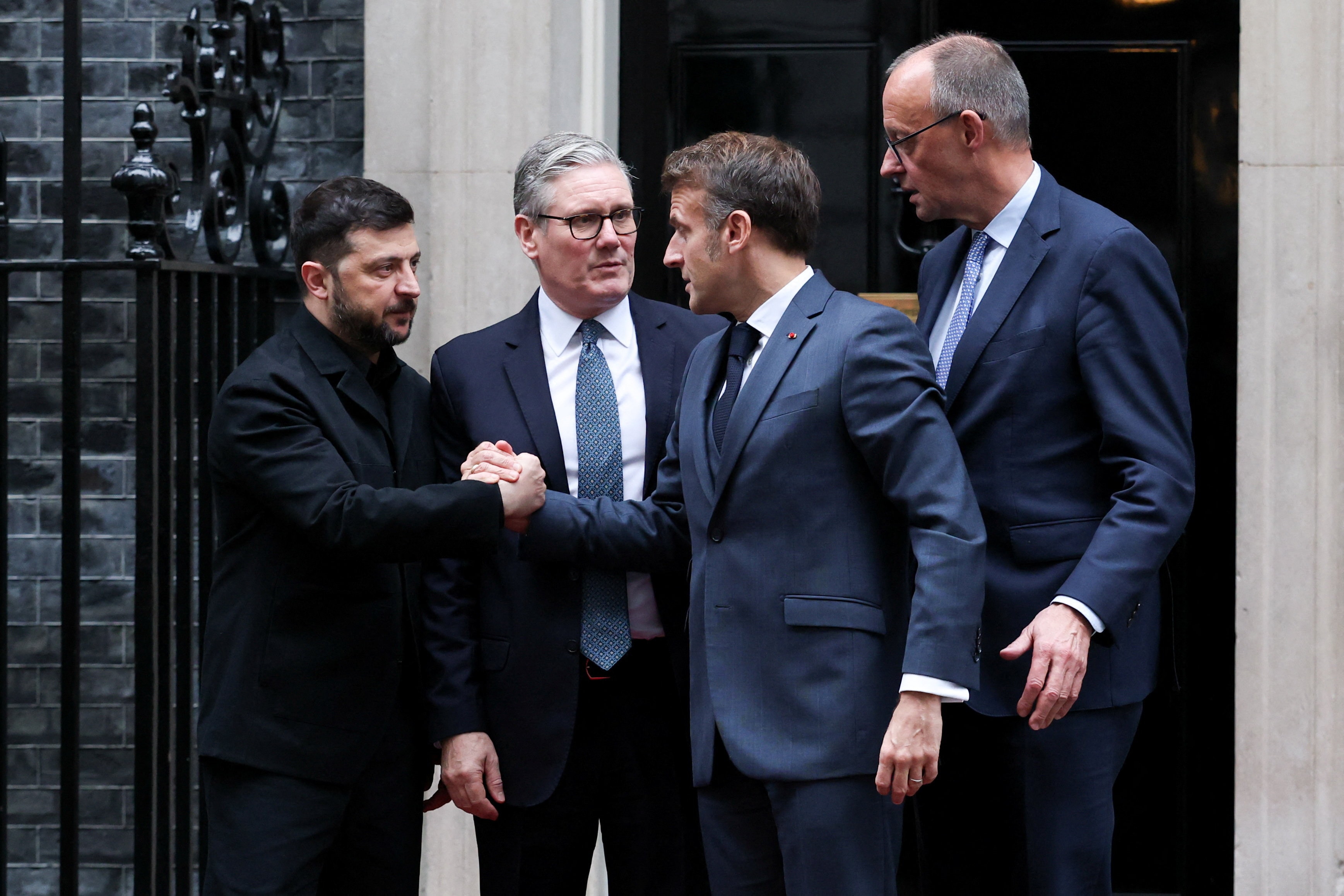 Tổng thống Pháp Emmanuel Macron bắt tay Tổng thống Ukraine Volodymyr Zelensky, bên cạnh Thủ tướng Đức Friedrich Merz và Thủ tướng Anh Keir Starmer, tại London, Anh, ngày 8/12/2025. (Ảnh: Reuters)