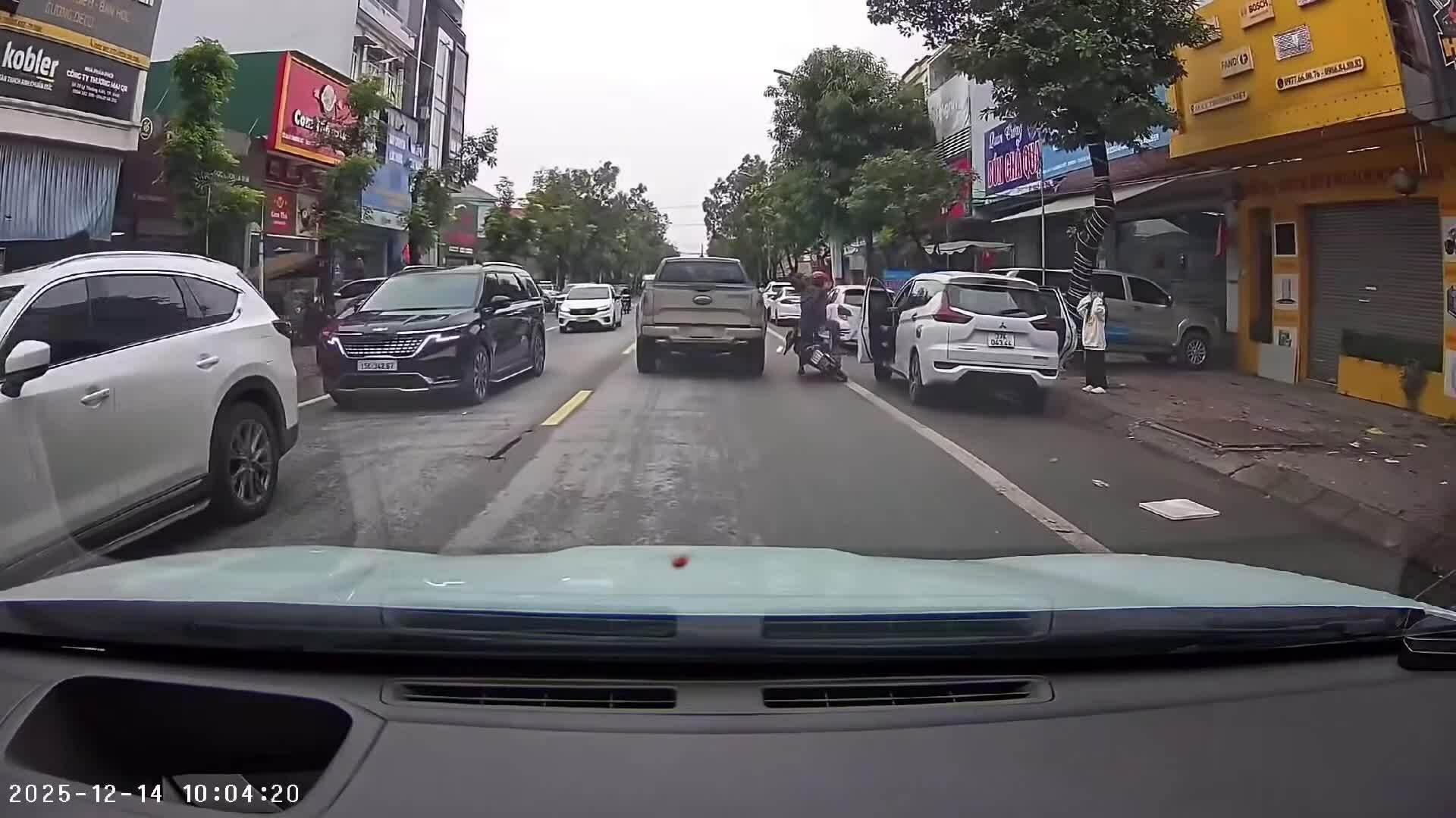 Đi xe máy nghe điện thoại, người đàn ông bị cửa ôtô bật mở xô ngã