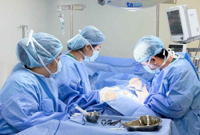 Bác sĩ Tuấn (phải) và êkíp phẫu thuật giải phóng vành tai cho bệnh nhi. Ảnh: Giản Đơn