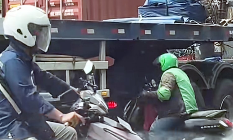 Người đi xe máy chui qua gầm xe container ở đám tắc đường