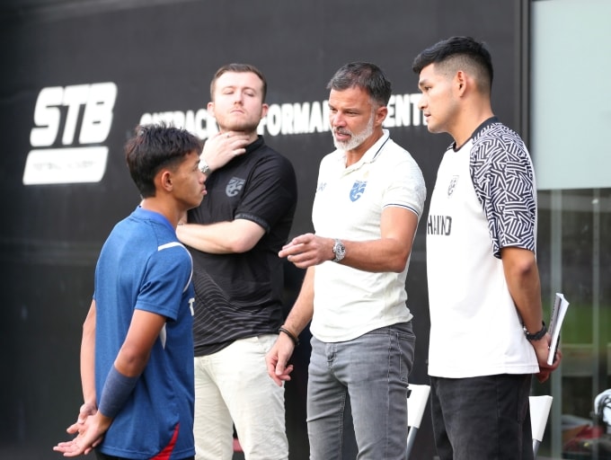 HLV Anthony Hudson (thứ hai từ phải sang) trao đổi với tiền vệ Thái Lan Iklas Sanron trước buổi tập tại sân bóng thuộc Học viện STB ở Bangkok vào chiều 17/12/2025, một ngày trước chung kết SEA Games 33. Ảnh: Hiếu Lương