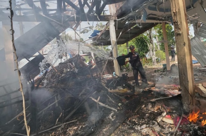 Tình nguyện viên đang dập tắt đám cháy tại một ngôi nhà mà quân đội Thái Lan cho biết đã bị trúng đạn pháo của Campuchia ở tỉnh Sisaket, Thái Lan, ngày 14/12. Ảnh: AP