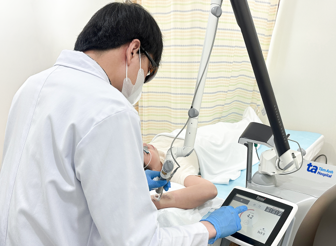 Bác sĩ Thiện điều chỉnh bước sóng laser phù hợp với từng màu mực để xóa xăm cho chị Mai. Ảnh: Bệnh viện Đa khoa Tâm Anh