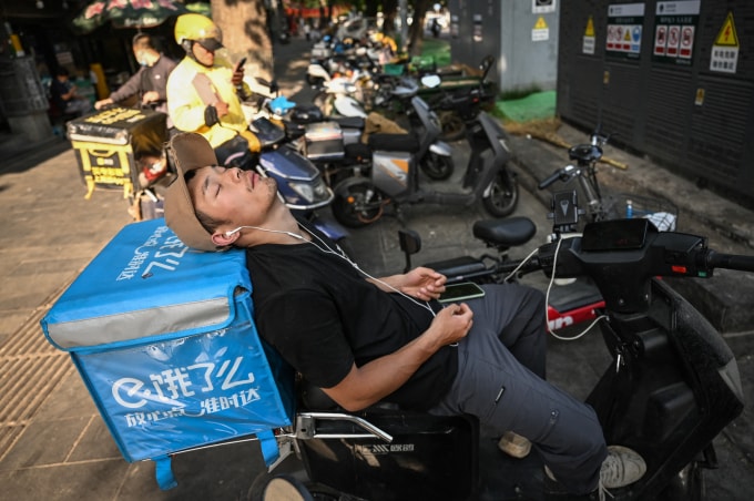 Tài xế giao đồ ăn tranh thủ chợp mắt trên một con phố ở Bắc Kinh hồi tháng 5/2024. Ảnh: AFP