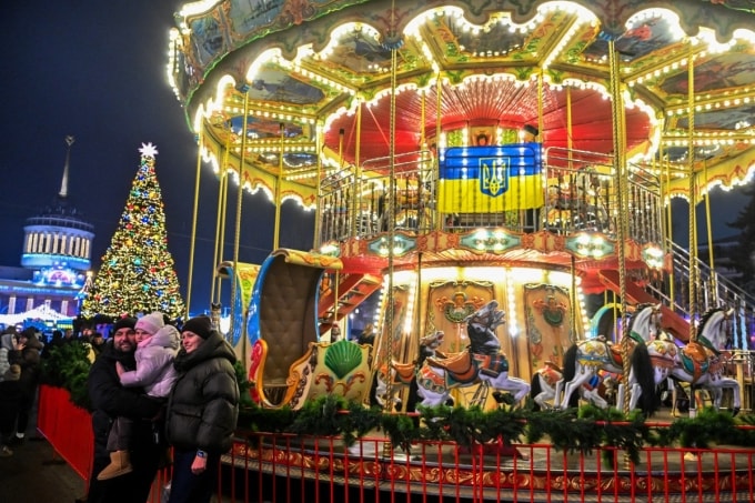 Một gia đình người Ukraine chụp ảnh trước vòng quay ngựa gỗ trong khu chợ Giáng sinh ở Kiev ngày 21/12. Ảnh: AFP