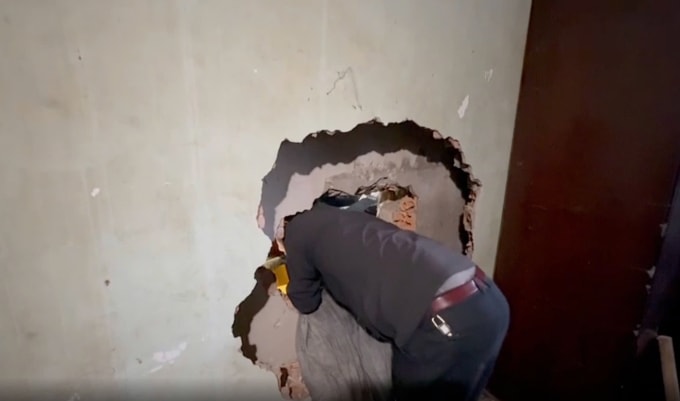 Bức tường giữa 2 căn nhà được lực lượng chức năng phá vỡ để tiếp cận hiện trường cứu nạn. Ảnh: Ngọc Oanh