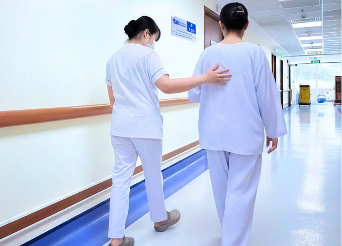 Kỹ thuật viên hướng dẫn tập vật lý trị liệu cho bà Trân trước khi xuất viện. Ảnh: Bệnh viện Đa khoa Tâm Anh