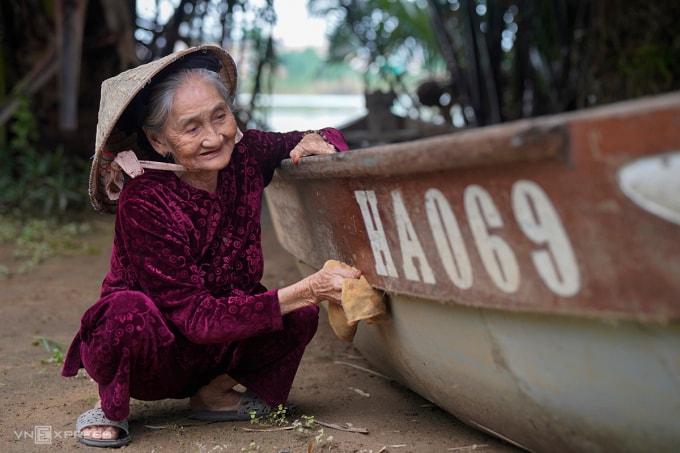 Cụ Xong lau chùi con thuyền do nhiếp ảnh gia Pháp tặng, như cách gìn giữ ký ức. Ảnh: Nguyễn Đông