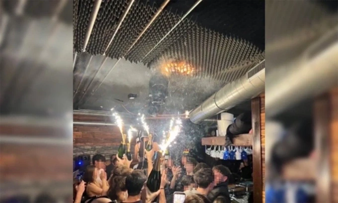Khách và nhân viên quán Constellation Bar nâng sâm panh, dường như khiến trần bén lửa. Ảnh: CNN