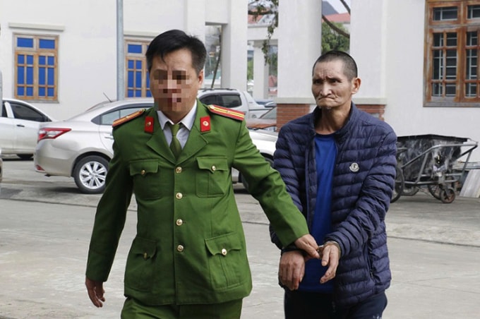 Nghi can Xìa (góc trái), bị cảnh sát dẫn giải về trụ sở. Ảnh: Công an cung cấp