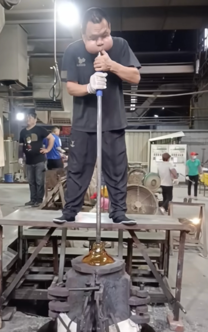 Anh Zhang, 48 tuổi, đang phồng má thổi thủy tinh tại xưởng chế tác ở Trung Sơn, tỉnh Quảng Đông, Trung Quốc, tháng 12/2025. Ảnh: Sina