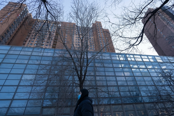 Một phụ nữ đi ngang qua khu chung cư tại quận Xương Bình, vùng ven Bắc Kinh, ngày 24/12/2025. Ảnh: AP.