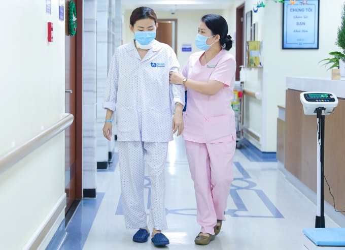 Nhân viên y tế hướng dẫn chị Hòa vận động nhẹ nhàng sau phẫu thuật. Ảnh: Trung Vũ
