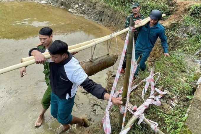 Các lực lượng khiêng quả bom từ ruộng để đưa vào thùng xốp. Ảnh: Trọng Quốc