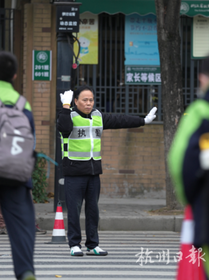 Ông Wu Bin,  Hiệu phó trường Trung học số 14 Hàng Châu tự nguyện đứng ra phân luồng giao thông mỗi sáng trước cổng trường. Ảnh: Hangzhou Daily