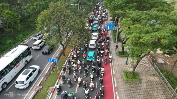 Một người đi xe đạp chạy lên vỉa hè trong khi làn ưu tiên bị xe máy tràn vào. Ảnh: Đình Văn