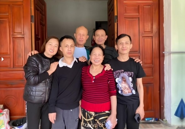 Anh Hoàng (thứ hai từ trái sang) chụp ảnh lưu niệm bên mẹ (áo đỏ) và người thân, tháng 11/2025. Ảnh gia đình cung cấp