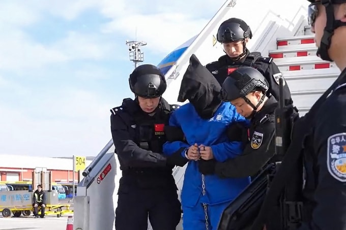 Cảnh sát Trung Quốc áp giải Chen Zhi rời máy bay tại Bắc Kinh ngày 8/1. Ảnh: AFP
