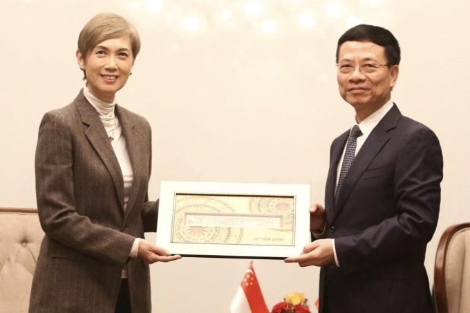 Bộ trưởng Nguyễn Mạnh Hùng tặng quà lưu niệm là một bộ tem Việt Nam cho Bộ trưởng Phát triển Kỹ thuật số và Thông tin Singapore, sáng 16/1. Ảnh: Doãn Mạnh