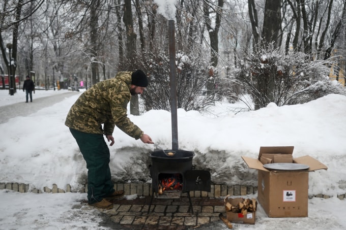 Một tình nguyện viên đang rán bánh trên bếp lò tại một điểm trợ giúp tại công viên ở Kiev ngày 15/1. Ảnh: AFP