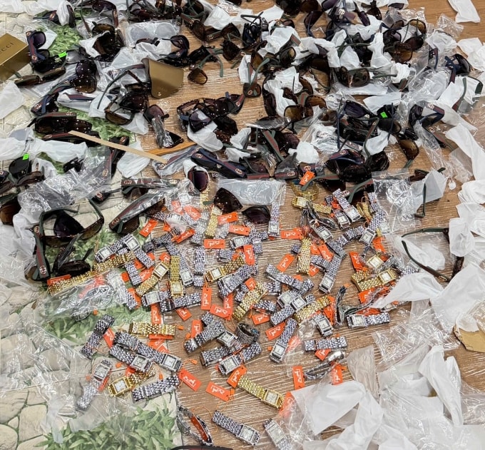 Kính mắt nhái Gucci và đồng hồ Hermes nhái của nữ tiểu thương bị tịch thu. Ảnh: Văn Vũ