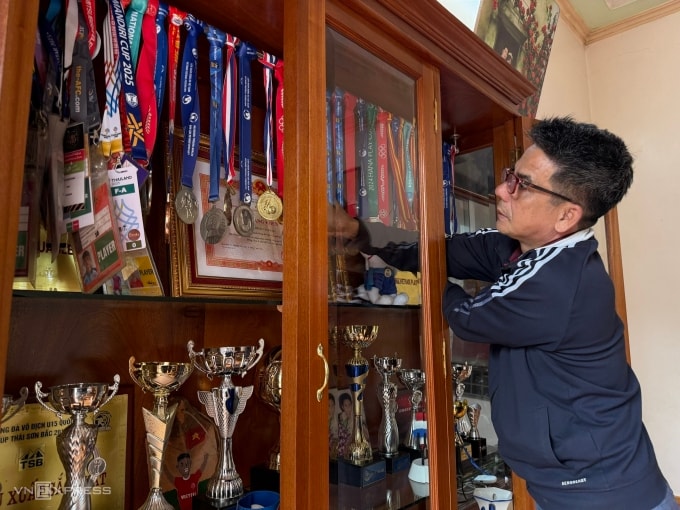 Ông Khuất Văn Dẩu, 54 tuổi, bố của cầu thủ Khuất Văn Khang đang sắp xếp lại loạt huy chương, cúp của con trai, tại nhà riêng ở thôn Phương Sen, xã Phúc Lộc, Hà Nội, sáng 20/1. Ảnh: Nga Thanh