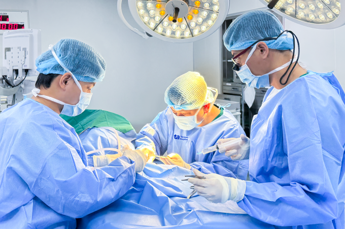 Bác sĩ Tuấn (ở giữa) phẫu thuật điều trị vết thương gót chân trái cho bé Toàn. Ảnh: Giản Đơn