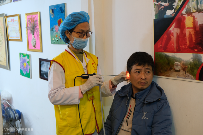 Bác sĩ Đỗ Thị Thành, từng công tác tại Bệnh viện E Hà Nội, thăm khám tai cho một bệnh nhân, tại quán cà phê trên phố Yên Lãng, phường Đống Đa, sáng 10/1. Ảnh: Quỳnh Nguyễn