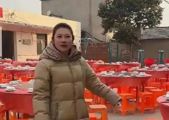 Nữ blogger ở tỉnh Giang Tô đứng cạnh 100 mâm cỗ đã chuẩn bị hôm 24/1 nhưng không ai đến ăn. Ảnh: Sohu