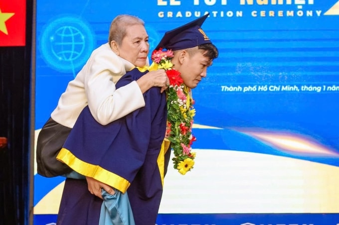 Trí Dũng cõng mẹ lên sân khấu nhận bằng tốt nghiệp Dược sĩ loại xuất sắc, ngày 24/1. Ảnh: NTTU