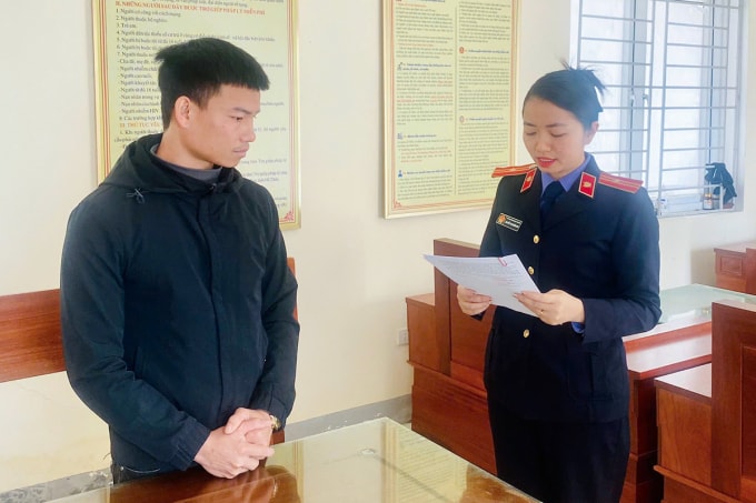 Nghi can Đạt (góc trái) nghe kiểm sát viên đọc lệnh khởi tố. Ảnh: Hùng Lê