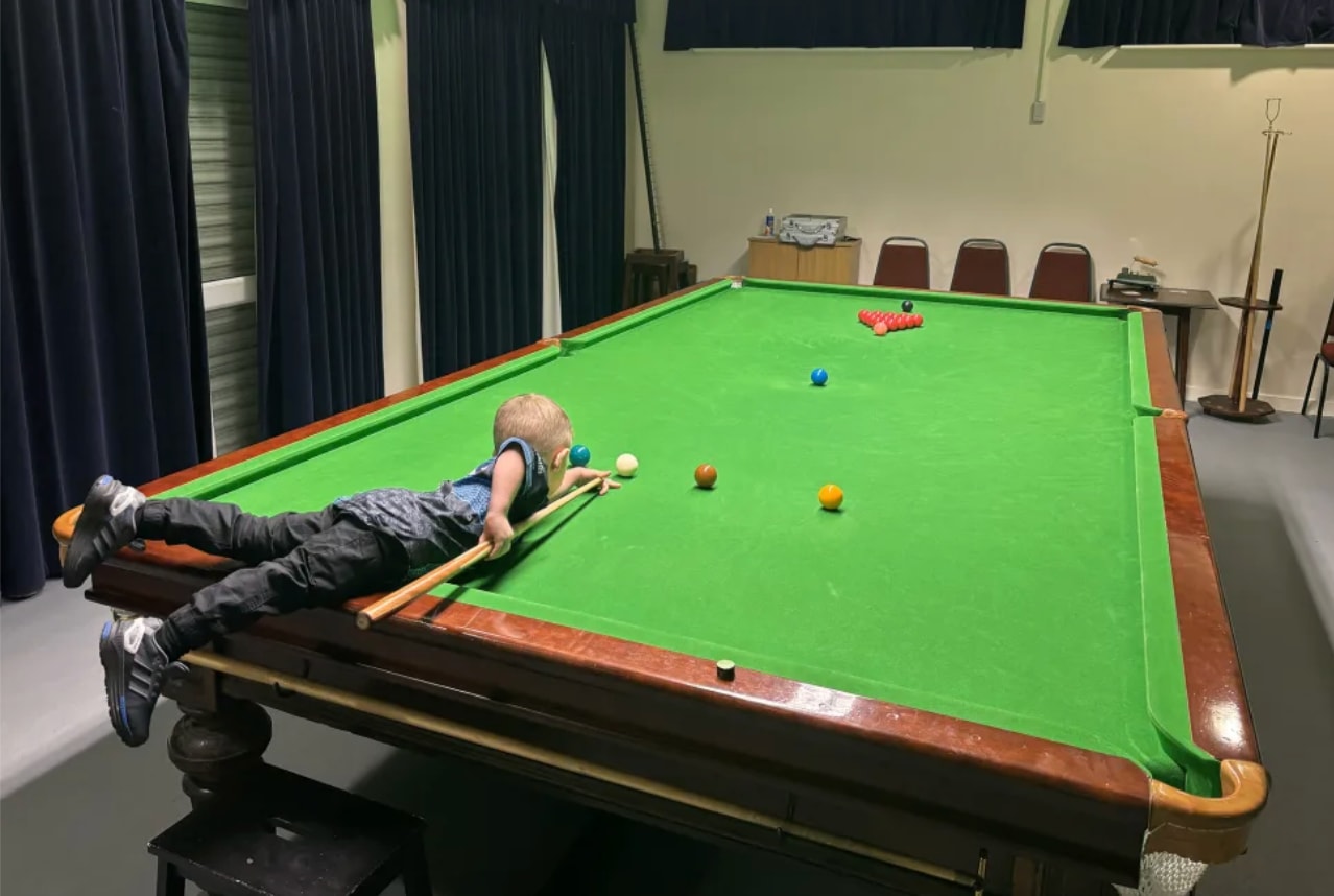 Jude phải dùng ghế đẩu để với tới bàn snooker cỡ người lớn. (Nguồn: GWR)
