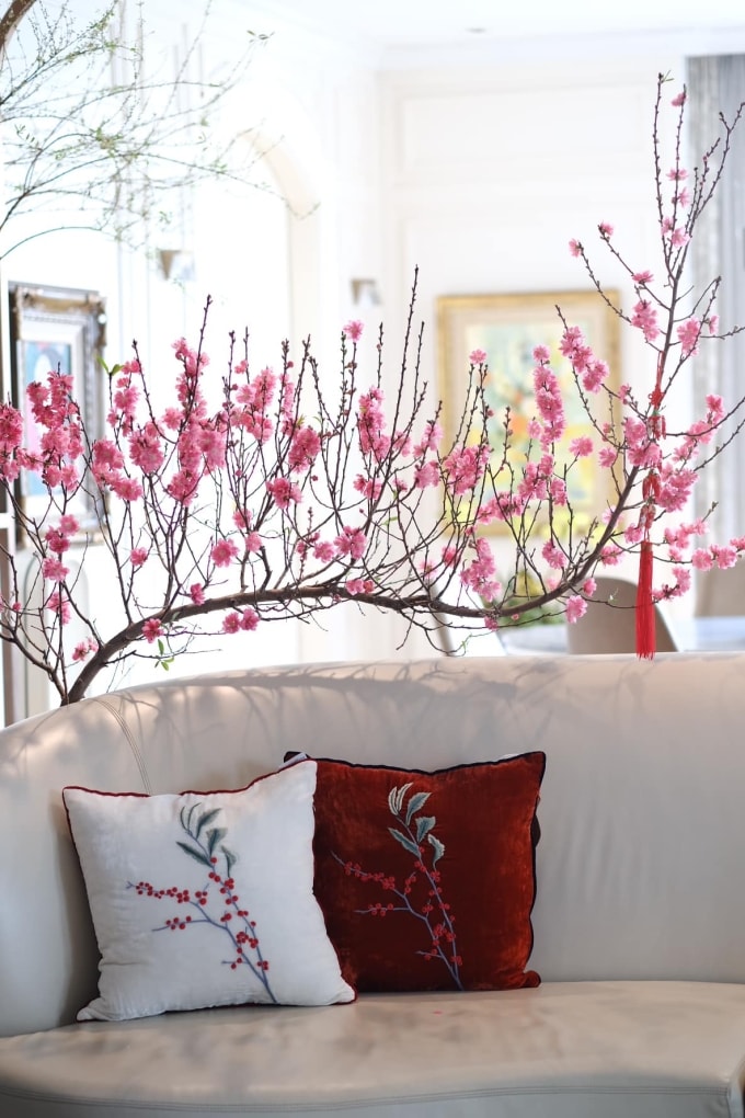 thay vì đặt nhiều chậu lớn chiếm diện tích sàn, chỉ sử dụng một cành đào tạo điểm nhấn phía sau sofa, giúp phòng khách vẫn có không khí Tết mà không ảnh hưởng lối đi và công năng sinh hoạt. Ảnh: Hoàng Lan
