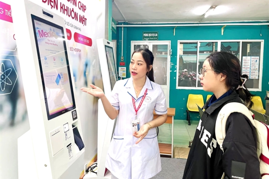 Một y tá giúp bệnh nhân đăng ký lịch hẹn khám bệnh bằng ki-ốt tự phục vụ thông minh tại một bệnh viện ở TP.HCM
