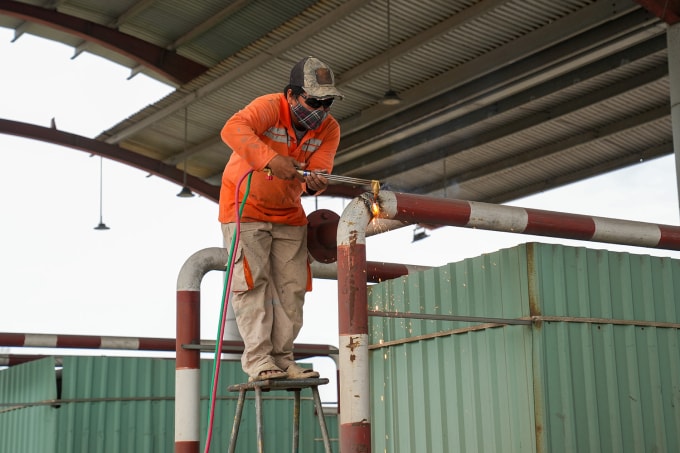 Công nhân dùng đèn khò cắt tháo dỡ hạng mục kết cấu thép tại trạm thu phí T3. Ảnh: Trường Hà