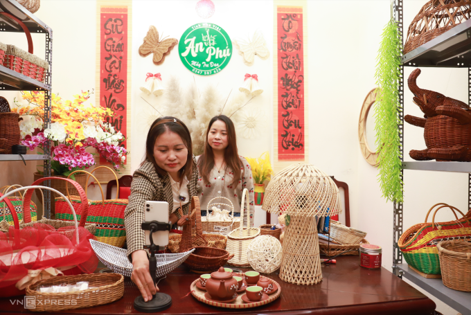 Chị Đặng Thị Kim Thêu, 42 tuổi, chỉnh góc máy, chuẩn bị livestream tại phòng trưng bày sản phẩm tại làng nghề mây tre đan Phú Túc (xã Phượng Dực), chiều 23/1. Ảnh: Quỳnh Nguyễn